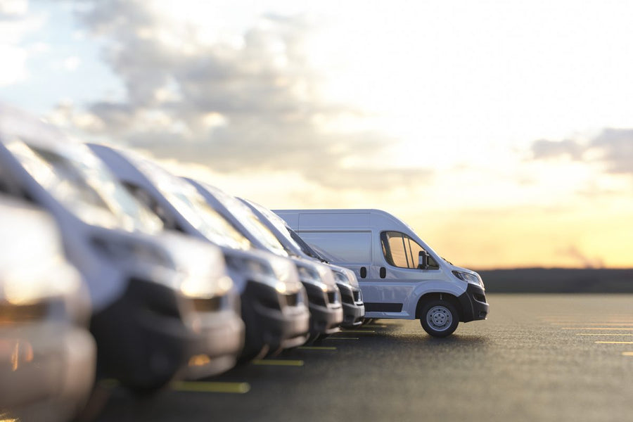 A row of white fleet vans parked at sunset