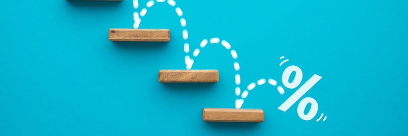 Percent sign stepping down a staircase of wooden blocks on a blue background