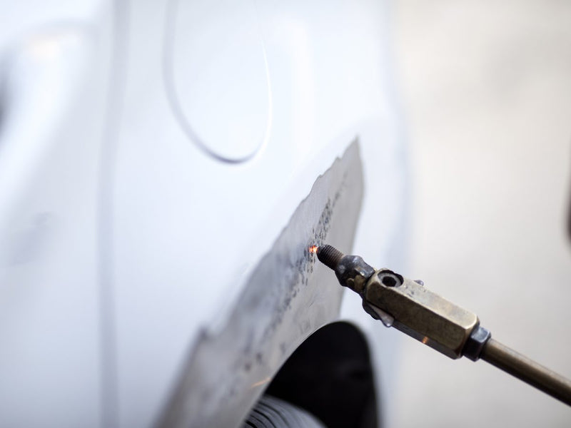 Technician drilling out a spot weld on a car panel