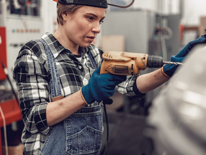 Technician drilling a hole in a car body panel