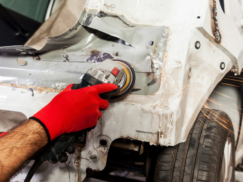 Technician stripping a rusted wheel arch with a disc