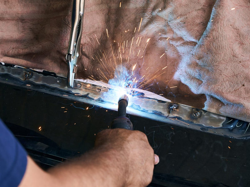 Technician MIG welding a car body panel